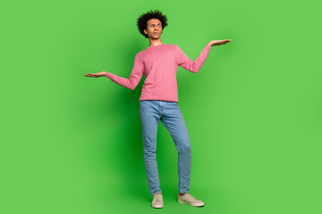 Full length photo of doubtful unsure guy dressed pink pullover showing arms scales emtpy space isolated green color background