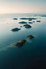 Aerial view of a group of small, scattered islands in a vast ocean, focusing on the contrast between the land and water. Emphasize the isolation and simplicity of the scene. 