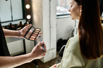 A makeup artist enhances the features of a female client with skillful application.