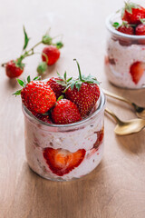 A wholesome and nourishing breakfast of overnight oats with yogurt and fresh strawberries, served in glass jars on a rustic wooden table. Soft, diffused light creates a warm and inviting atmosphere