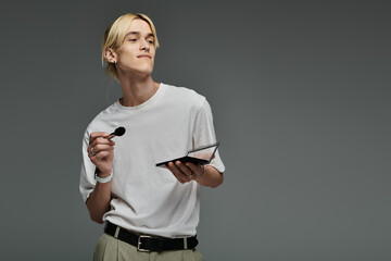 Handsome man multitasking with a palette of makeup.