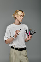 A man holding a variety of colorful brushes.