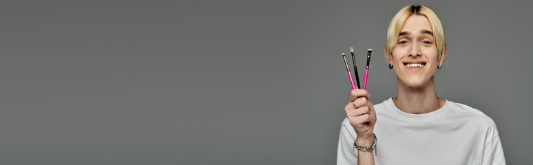 A man holds up brushes in front of his face.