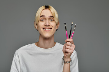 Man confidently holds three brushes in his hand.