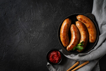 Bavarian sausage on black plate or pan, parsley, tomato sauce