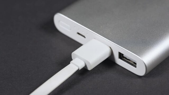 Modern convenient two port usb charger for devices. Close up of male hand plugging cables into power outlet. Portable autonomy charger. Modern technology concept
