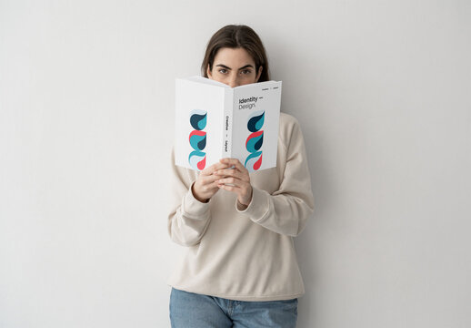 Mockup of woman holding customizable book in studio