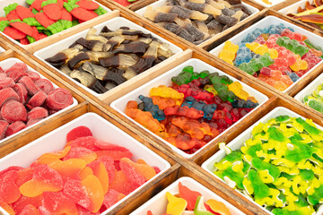 Colorful assorted gummy candies on trays for sale on marketplace. Full frame