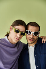 two men wearing sunglasses pose together for a picture.