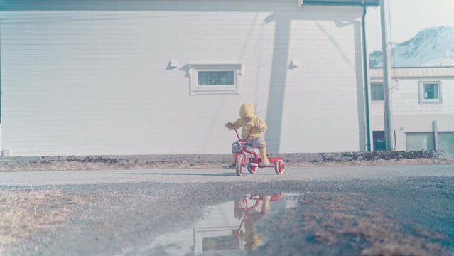 Boy rides a tricycle on a quiet road in Northern Norway in Tromvika right outside of Tromso, Norway. With big mountains in the background, a stunning capture. #untraceableglobal