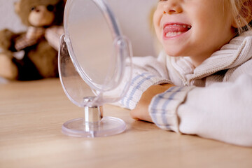blonde girl of 4 years old girl in front of mirror engaged with speech therapist, gymnastics for...