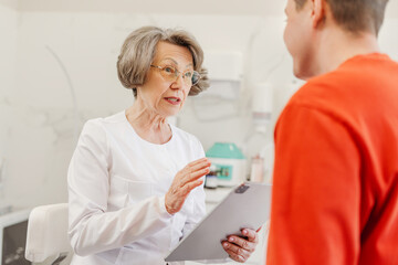 Obraz premium Attractive, senior, mature female cosmetologist communicates with patient, asking about health