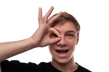 Positive Caucasian fair-haired teenager guy smiling at the camera on a studio background