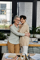 Two women in office, sharing a warm hug.