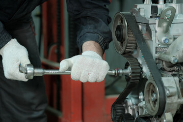 Car engine repair at the service center. An auto mechanic performs work on replacing the timing...