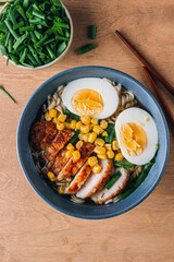 A mouthwatering bowl of chicken ramen served on a rustic wooden table, accompanied by chopsticks. The warm lighting and natural wood elements create an inviting and cozy atmosphere.