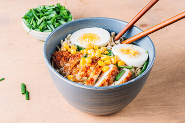 A mouthwatering bowl of chicken ramen served on a rustic wooden table, accompanied by chopsticks. The warm lighting and natural wood elements create an inviting and cozy atmosphere.