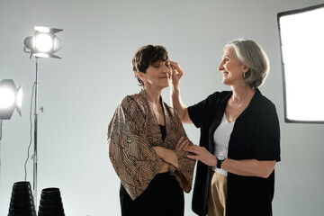 A middle-aged lesbian couple in a photo studio, one woman gently touching her partner