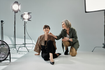 Fototapeta premium A middle-aged lesbian couple poses in a studio - one as photographer, the other as model.