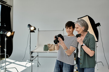 A woman in a photo studio takes a picture while using a camera, in a collaborative and creative...