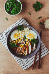 A mouthwatering bowl of chicken ramen served on a rustic wooden table, accompanied by chopsticks. The warm lighting and natural wood elements create an inviting and cozy atmosphere.