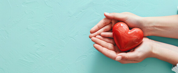 Adult and child hands holding a red heart on an aqua background symbolize heart health, donation, corporate social responsibility, World Heart Day, World Health Day, and Family Day.