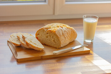 fresh white sliced bread and a glass of milk on wooden table in the kitchen