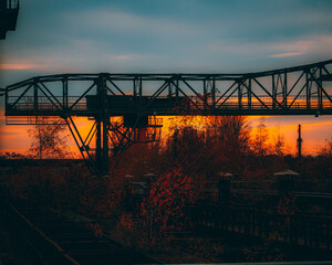 a train track bridge that is over the train tracks in the sunset