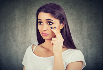 woman pulling down eyelid checking her eye looking in morrow feels unwell has black circles