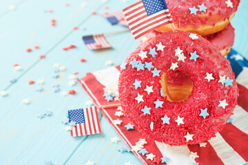 Obraz premium Patriotic sweet donuts 4th july with american flag. Delicious american donuts with red icing and blue and red stars toping on blue background. Dessert food for American Independence Day celebration.