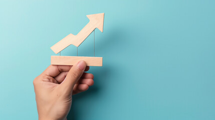 hand holding wooden profit growing graph icon sign isolated on blue background concept of business growth and profit increase, copy space for text