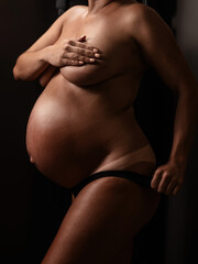 Fototapeta premium Pregnant woman pulls back her panties showing instant tan. Vertical photo. 