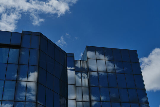 A glass skyscraper with clouds reflected as if in a mirror. An office building with many floors. A small town in Serbia - Zrenjanin. Vojvodina District.