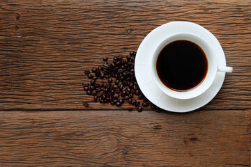 A cup of black coffee  with beans on wood