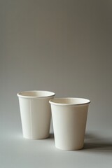 Two beige paper cups on a neutral background with soft falling light. Mockup. Vertical orientation