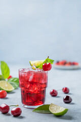 Cherry-lime mojito cocktail with mint, lime and ice on a light background with fresh berries.
