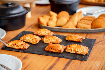 A beautifully arranged buffet table showcasing a variety of appetizers and snacks, including meat dishes, fried pastries, ready for guests to enjoy a delightful meal.