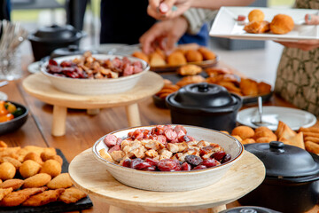 People enjoying a buffet-style meal, serving themselves from a variety of dishes including appetizers and snacks, creating a casual and inviting atmosphere for social dining.