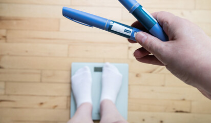  Ozempic Insulin injection pen for diabetics and weight loss. Woman weighs herself and holds...