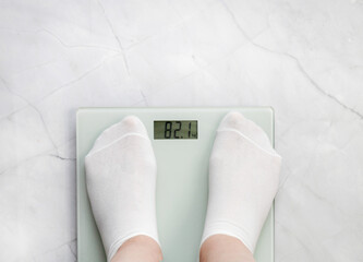 Feet in white socks stand on scales. Weight loss and diet concept.