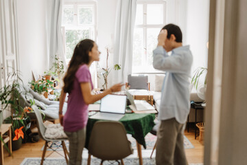 Defocussed image of siblings arguing while studying at home