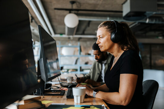 Focused female programmer coding while sitting at desk in tech start up office