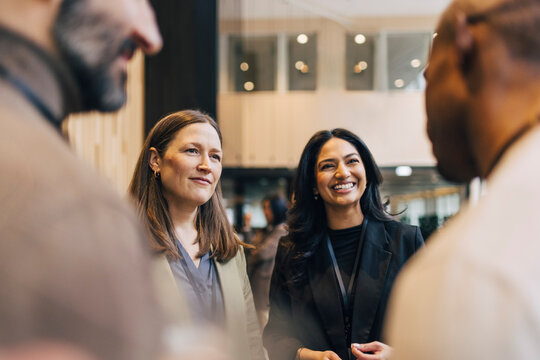 Female entrepreneurs talking with male delegates during networking event at convention center