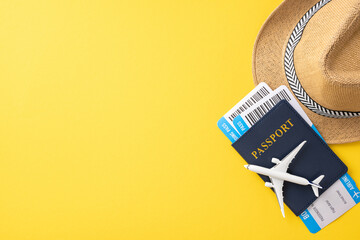 Travel essentials including a passport, boarding passes, a straw hat, and a toy airplane on a...