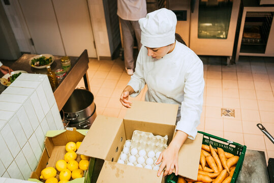 High angle view of female chef counting eggs while standing at commercial kitchen