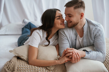 Together on the bed. Young couple are at home