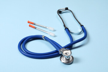 Stethoscope and syringes on light blue background, closeup. Medical tools