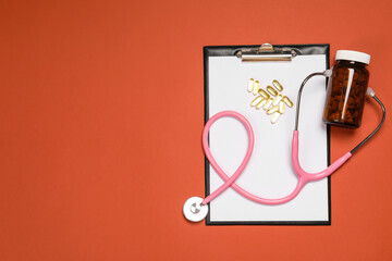 Stethoscope, pills and clipboard on crimson background, flat lay. Space for text