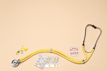 Stethoscope and pills on beige background, flat lay. Space for text