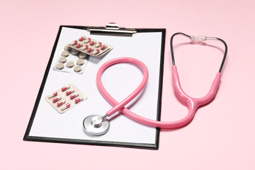 Stethoscope, clipboard and pills on pink background. Medical tool